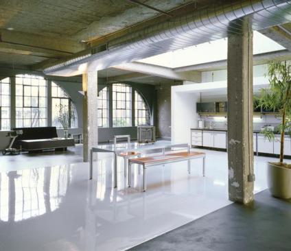 The entire loft was stripped to bare concrete.Walls were sandblasted for a raw but clean finish. A self-leveling layer of concrete smooths out the floor, and a band of glossy industrial epoxy defines the dining zone.