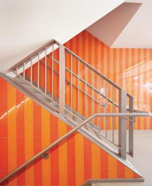 The building?s largely quiet color palette is broken up by a vivid orange internal stair that serves all levels.