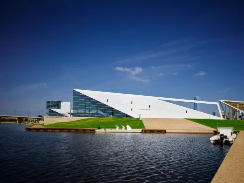 The east elevation is parallel to a river inlet allowing rowing shells to access the river via a concrete ramp.  The inlet size allows for a 60’ long boat to maneuver.  The open beam frames Downtown.  The gold “notes” are rhythmically placed on the façade. 