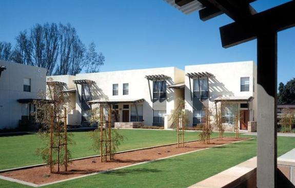 The buildings' edges form an outdoor room, while an overscaled wooden trellis clearly marks the community's pedestrian entry.
