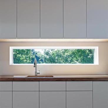 Laminated red and white oak planks make up the kitchen countertops, while the windows offer views of the trees.