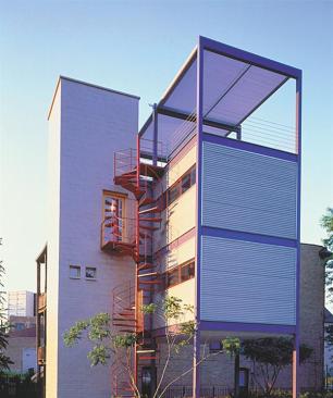 Rooted to earth, the polished concrete block stair tower contrasts with the lightness of the structural steel bays. A door to the roof draws air up through the house like a fan. The spiral fire escape adds sculpture to the back of the house.