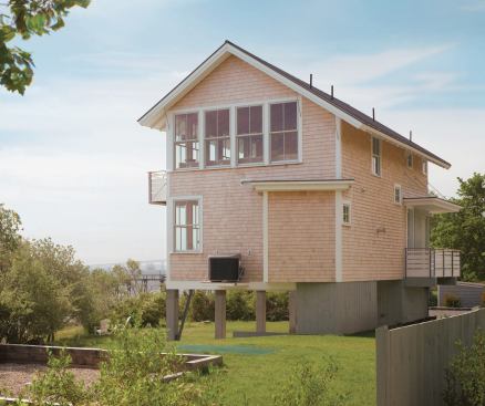 Perching above flood-prone shores, this 1,440-square-foot cottage makes efficient use of its narrow site, provides privacy by grouping service spaces along its street side, and positions living areas to take advantage of spectacular views.