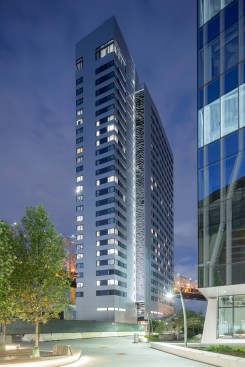 Exterior view of The House, by Handel Architects, at dusk, with a corner of The Bridge, by Weiss/Manfredi Architecture/Landscape/Urbanism, at right.
