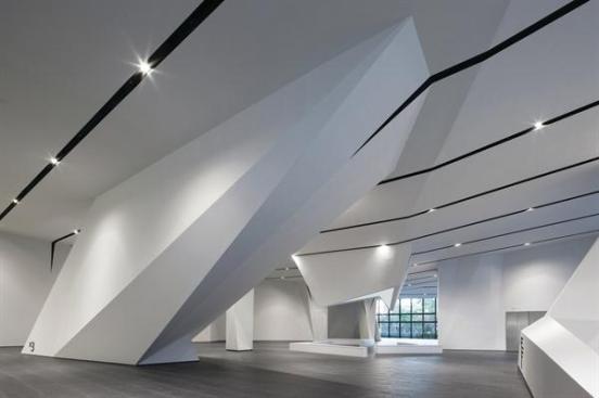 The+ground+floor+forms+a+sort+of+hypostyle+hall%2c+with+the+articulated+ceiling+plane+extending+to+the+ground+to+encase+columns%2c+elevators%2c+and+escalators.+The+stone+tiles+that+line+the+space+are+part+of+the+flooring+detail+system+designed+by+NADAAA%2c+which+aims+to+continue+the+exterior+plaza+into+the+building.