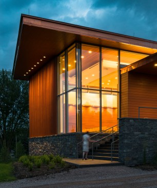 The building is clad with horizontal and vertical cedar on a granite fieldstone base.