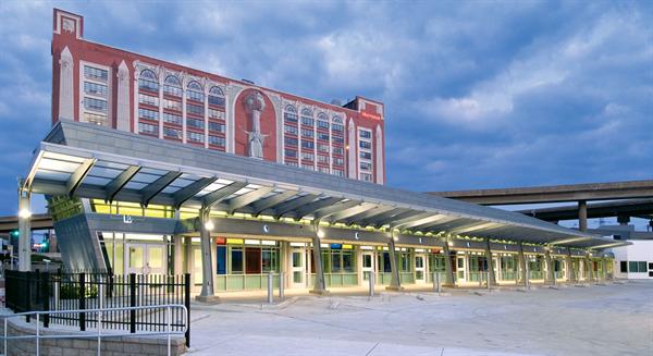 A 1984 mural by artist Richard Haas on the nearby Sheraton St. Louis City Center hotel overlooks the Gateway Transportation Center's north wing, which incorporates 10 canopied bays for Greyhound buses. The exterior is clad in zinc panels from Rheinzink, which can withstand the grit and chemicals that the highway overhead will shed onto the building.