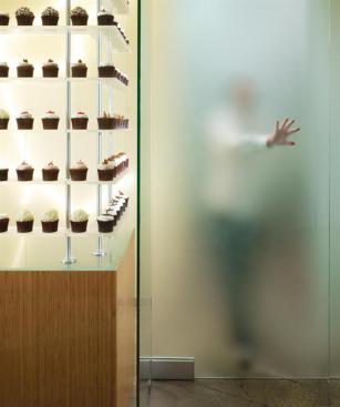 In pursuing the strategy of a bakery that doesn't look like a bakery, one thing the team did not want to sacrifice was the cachet that each cupcake is made on-site. A frosted glass door shielding the kitchen allows customers to see shadows of chefs, smell the baking cake, and hear the whir of the mixers, without seeing spilled flour and messy pastry bags.