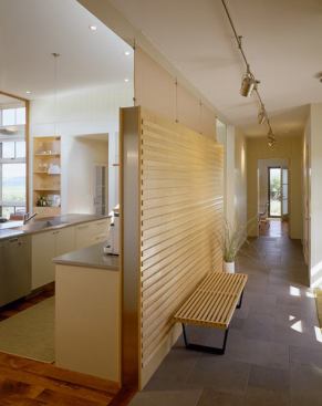 A paneled wall topped with translucent panels screens the kitchen great room from the entry.