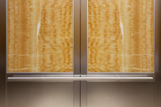 CabForms Series 2000-N Elevator Interior with upper inset panels in ViviStone Honey Onyx, Pearlex finish; lower inset panels in Stainless Steel, Linen finish; stiles and rails in Stainless Steel, Seastone finish; Sextant Handrail in Stippled Stainless Steel at the Woolworth Building, Eugene, Oregon