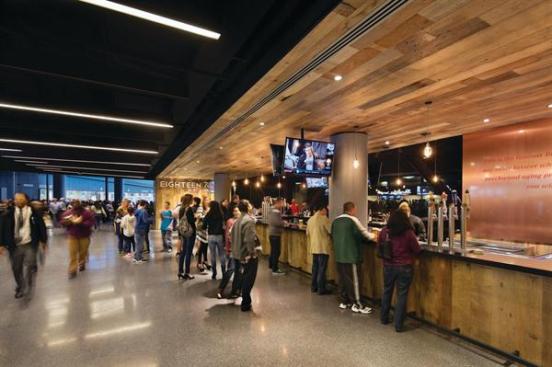 Along+the+concourse%2c+public+areas+are+marked+by+a+rhythmic+progression+of+strip+lights+across+the+ceiling+plane.+Concessions+are+wrapped+in+warm+wood+to+counter+the+overall+black+and+gray+interior.+