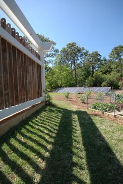 Due to roof orientation, the solar panels were ground-mounted in the rear yard behind the garden. Drought-tolerant plants were used, as well as zone- and rain-delay-controlled irrigation. Wood from the existing fence was reused for decorative semi-private fencing around the carport and side deck.