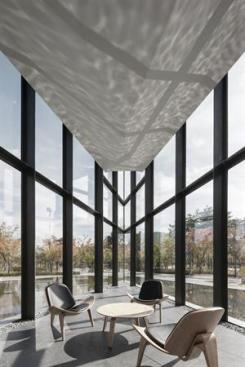 The+west+end+of+the+building+comes+to+a+sharp+point+that+houses+seating+for+a+caf%c3%a9.+The+bases+of+the+steel+mullions+are+covered+by+river+rocks+to+mask+imperfections+in+the+construction%2c+and+to+mark+the+transition+from+outside+to+inside.