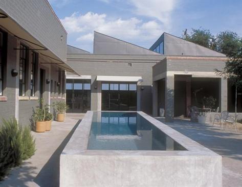 A raised lap pool cools off the courtyard, while the sawtooth roof floods the interiors with light.