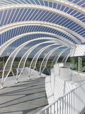 A white-painted pergola shades an outdoor terrace and plaza while reducing solar load on the building.