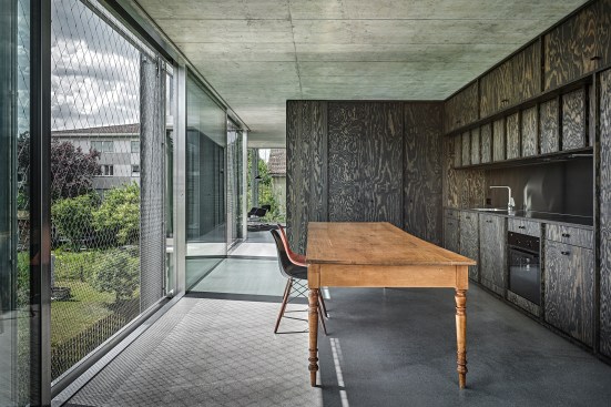 A dark oiled maritime pine structure divides rooms and holds kitchen appliances, storage, and bathroom fixtures.