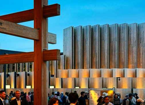 The Japan Pavilion, designed by Oki Sato and Nikken Sekkei, features vertically oriented cross-laminated timber (CLT) planks arrayed in a series of rings that emanate radially from the center.