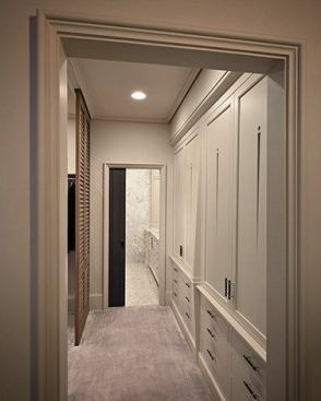 The walkway to the bathroom features a custom linen press cabinet and cypress louvered doors separating the walk-in closet.