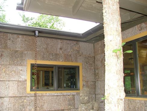 Adding to the rustic look, the Chandler Design-Build house features Highland Craftsman’s Bark House shingle siding, which is reclaimed from trees harvested for other uses, log pillars, and rain chains.