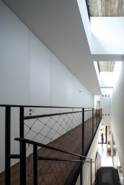 Clerestories allow diffuse northern light to wash the walls of the second-floor hallway, which offers access to the family’s bedrooms and baths through doors that are aligned flush with the white walls.