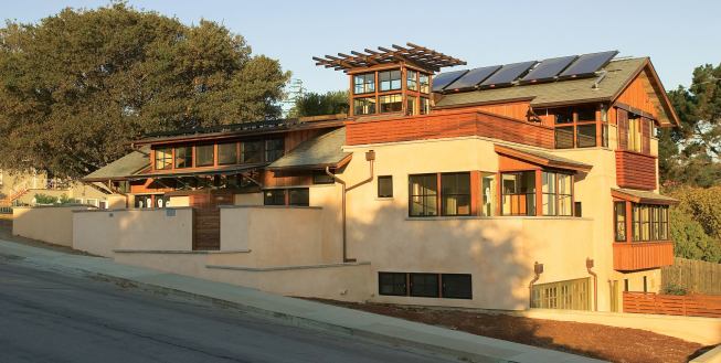 Thermal-mass walls, roof PVs, solar hot water collectors, and sand beds that store radiant heat are integrated into this urban house in Belmont, Calif. The garage doors came from an elementary school, and the roof is made of recycled tires.