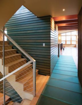 Inside the Johnson house, salvaged fir slats echo the exterior siding, and glass panels on the floor transmit light to a hallway below.