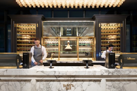 A large decorative pendant provides warmth at RH New York's cafe, supported with track-mounted spotlights to highlight the counters. Variable white linear LED fixtures highlight display casework.