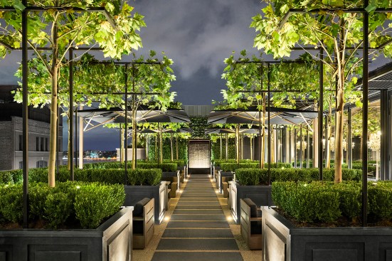 Visible from street level, the RH New York rooftop is warmly illuminated.