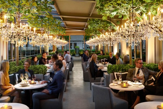 A custom narrow spot LED is integrated into each decorative pendant to highlight the dining tables at RH New York's rooftop restaurant.