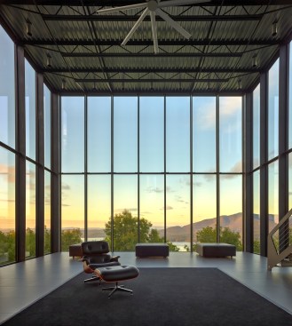 The steel T-section frame for the house’s glass enclosure is bolted to the concrete foundation for stability, and the thin profiles of the piers minimize disruption of the view over the valley below.