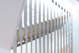 The design for the staircase is centered on folded stainless steel. Hung from a structural steel support on the top level of the townhouse, vertical folded pieces create a continuous screen that encloses the two above-grade flights of stairs. Tabs on the bent risers are fitted into slots on the vertical pieces, which created an easy setup for on-site construction and spot-welding.