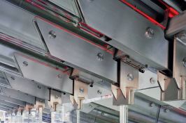 Glass stringer beams rely on the support of load-bearing glass walls to hold the weight of the booth's glowing red staircase and the tourists lounging upon it. The glass pieces are connected with stainless steel brackets and pins, but there is no load-bearing metal in the structure.