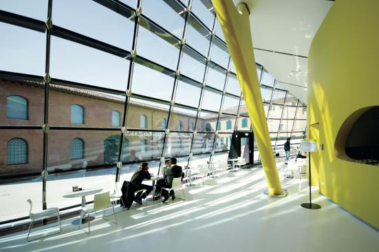 Café tables sit along the curving glazed curtainwall.
