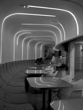 Hand-bent cold-cathode tubes wrap the all-white Waterlemon restaurant in syncopated illuminated stripes, while directional halogen accent lights extend from slots to highlight the tables.  