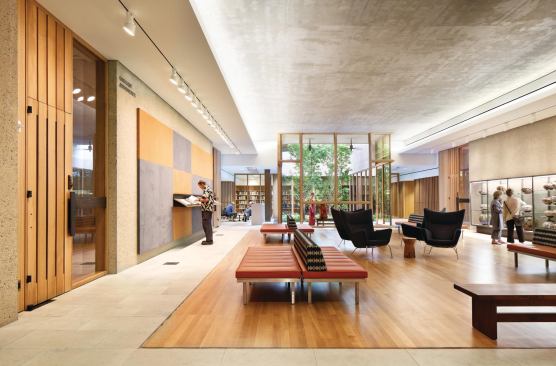In the lower level lobby area, the theme of natural light working in concert with electric light continues. Track-mounted PAR wallwashers illuminate the art on the walls, while a linear fluorescent covelight uplights the concrete-exposed ceiling. Daylight, from the gallery garden seen beyond, makes up the balance of illumination.