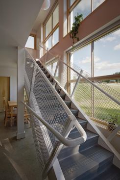 The stair screens the public spaces from the large south-facing windows, creating privacy for residents while utilizing solar gain. It is composed of durable vinyl treads, painted steel handrails, and lobster cage mesh for the guardrails.