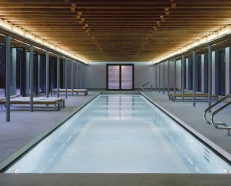 Low-voltage tungsten halogen fixtures define the perimeter edges of the pool volume, while four lines of custom designed linear fluorescent fixtures housed in perforated metal and integrated perpendicularly to the beam structure accent the length of the ceiling. 