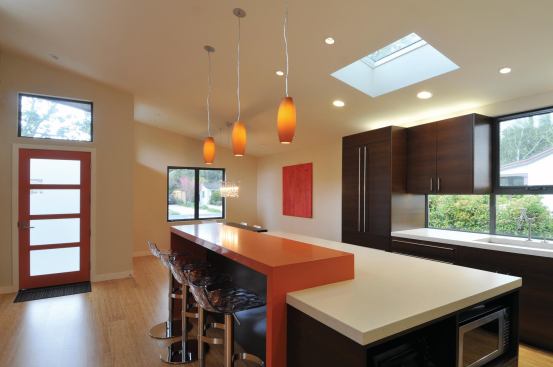 Skylights, a transom, and a wall of windows open up and brighten the kitchen and dining area. The kitchen features Concreteworks countertops with a rice hull finish, Caesarstone countertops in tequila sunrise, Woodmaster wenge cabinets, and appliances from Miele, Bosch, and Bluestar.