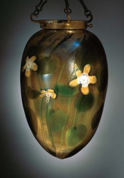The invention of iridescent, color-infused Favrile glass, considered Tiffany's greatest innovation, enabled craftsmen to embellish this blown glass lamp from the Fountain Court with variegated leaves and vines.