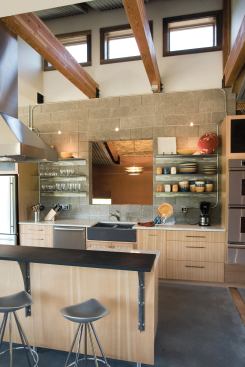 Appliances frame recycled steel shelves on the kitchen wall. Those touches of raw steel and exposed conduit fit Kelly's vision of a vacation home that has "aspects of a Portland loft mixed with a mountain lodge influence."