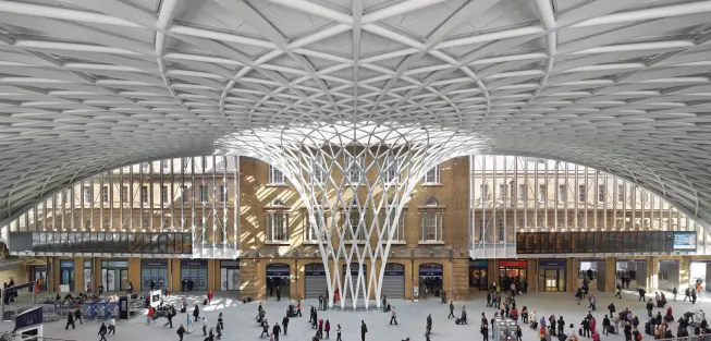 The glass, steel, and aluminum diagrid roof of the new Western Concourse at King’s Cross station spans out from a central woven funnel.
