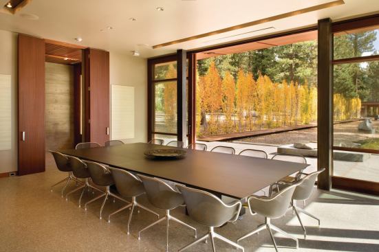 Polished brown concrete floors, mahogany built-ins, and exposed-aggregate concrete decks reinforce the colors and textures found on the site.